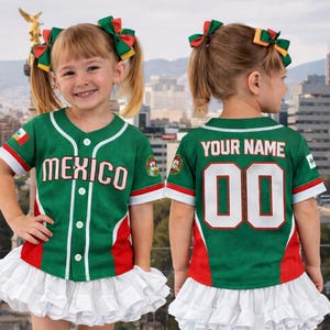 May include: A green baseball jersey with the word "MEXICO" in white, red, and green accents. The jersey has white sleeves and a red stripe at the bottom. Paired with a white ruffled skirt. The back of the jersey says "YOUR NAME" and has the number "00".