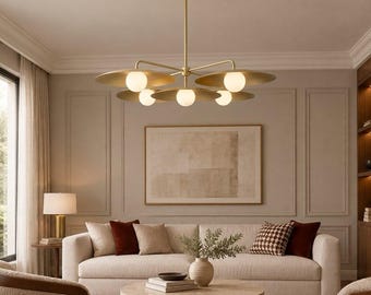May include: A brass chandelier featuring a central rod and four horizontal arms, each holding a flat circular disc and a spherical white glass light bulb. The fixture is suspended from the ceiling, providing illumination to the room below.