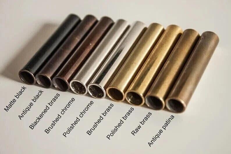 May include: An assortment of metal tubes in various finishes, including matte black, antique black, and polished brass. The tubes are arranged diagonally, showcasing a range of colors and textures. Text labels identify each finish, offering a visual guide to the different options.