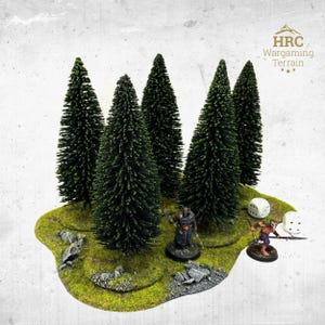 May include: A miniature wargaming terrain piece with a cluster of green pine trees on a grassy base. Two miniature figures and two dice are also present. The terrain is designed for tabletop gaming.