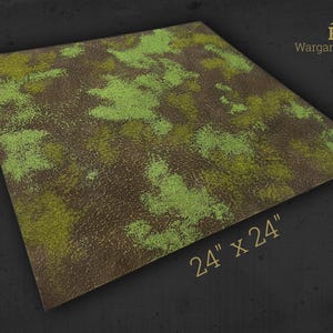 Op de afbeelding: Een vierkante wargaming terreinmat, 61 x 61 cm, met een getextureerd bruin en groen ontwerp. De mat heeft groene vegetatievlekken op een bruine basis, met de tekst "HRC Wargaming Terrain".