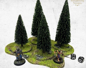 May include: A wargaming terrain set featuring four dark green pine trees on a textured, mossy green base. Two painted miniature figures stand on the base, one wearing blue and grey armor and the other in purple, with two black six-sided dice nearby.