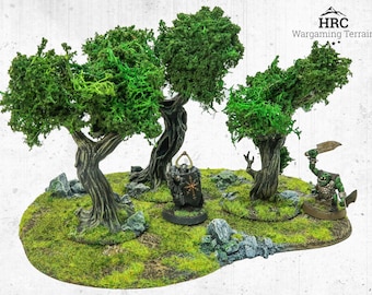 May include: A miniature wargaming terrain piece featuring three trees with green foliage and textured brown trunks. The base is covered in green moss and includes small rocks. Two miniature figures are present, one with a shield and the other an orc with a weapon. The logo "HRC Wargaming Terrain" is visible.