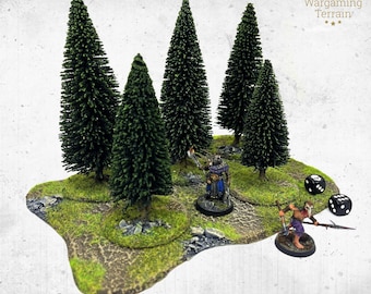 May include: A wargaming terrain piece featuring five dark green miniature pine trees on a textured, mossy green base with rocky details. Two painted miniature figures are positioned among the trees, accompanied by two black six-sided dice.