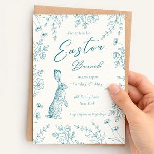 May include: An Easter Brunch invitation with a teal floral border and a standing rabbit illustration. The text reads "Please Join Us Easter Brunch 10am-12pm Sunday 5th May 188 Bunny Lane New York". The invitation is on a kraft paper card.