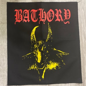 May include: Black square patch with the word "BATHORY" in red gothic lettering above a yellow goat head illustration. The patch has a raw edge.