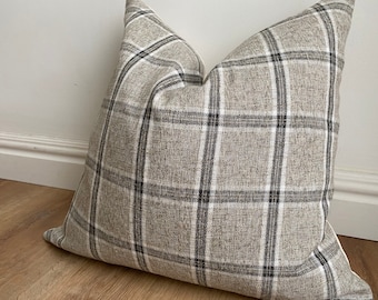 May include: A brown and white plaid throw pillow with a subtle black and white check pattern.