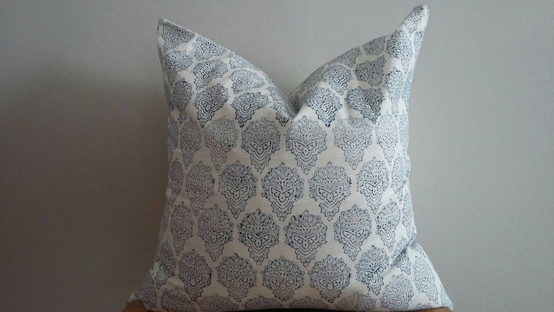 Puede incluir: Una almohada blanca con un patr&oacute;n damasco azul y blanco.