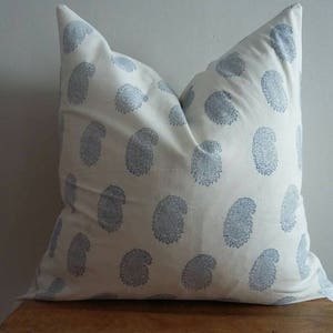 Puede incluir: Una almohada blanca con un patr&oacute;n de cachemira azul. La almohada est&aacute; hecha de una tela de algod&oacute;n suave y tiene un brillo sutil.