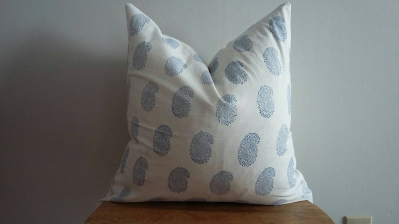 Puede incluir: Una almohada blanca con un patr&oacute;n de cachemira azul. La almohada est&aacute; hecha de una tela de algod&oacute;n suave y tiene un brillo sutil.