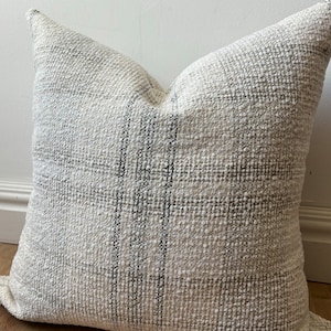 May include: A white and gray striped throw pillow with a textured woven fabric.