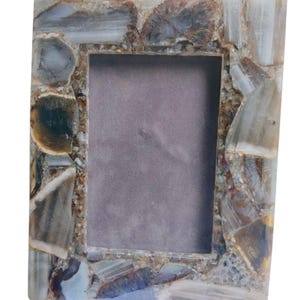 May include: Rectangular photo frame with a mosaic-like border. The frame's border is made of various shades of brown, gray, and white, creating a natural, stone-like appearance. The center opening is a muted gray color.