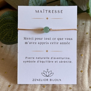 Könnte beinhalten: Armband mit einem hellgrünen Aventurin-Stein und einem goldenen Band. Auf der Karte steht der französische Text "MAÎTRESSE", ein Dankesspruch und der Name "ZENELIOR BIJOUX".