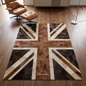Op de afbeelding: Een rechthoekig vloerkleed met een patchworkontwerp van koeienhuidstukken in bruin-, beige- en crèmetinten, gerangschikt in een Union Jack-patroon. Het kleed toont de tekst WOOLLEN ARTS in witte letters nabij het onderste centrale gedeelte.