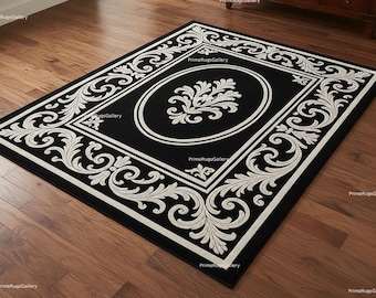 May include: Black rectangular rug with a white ornate border and central oval design. The rug features a detailed scrollwork pattern in white against a black background, suitable for home decor.