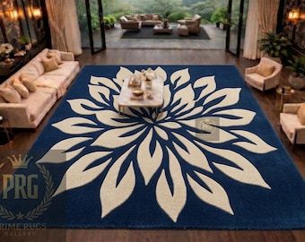 Puede incluir: Una alfombra grande, rectangular, azul marino con un diseño floral color crema. La alfombra está colocada en un salón con muebles y decoración. El diseño de la alfombra se asemeja a una flor grande.