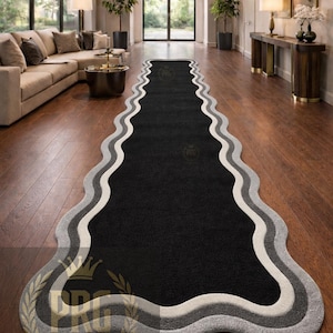 May include: A long, wavy-edged rug with a black center, bordered by white and gray bands. The rug is placed on a hardwood floor in a modern living space. The text "PRIME RUGS GALLERY" is visible.