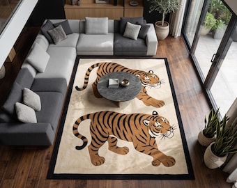 May include: A rectangular area rug featuring a cream-colored background with a black border and two large, stylized orange tigers with black stripes walking across the surface. The rug is positioned on a dark wood floor in a living room.