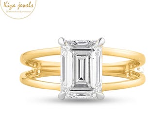 May include: A gold ring with a large, rectangular, clear gemstone. The ring has a split shank design. The brand logo "Kiza Jewels" is in the upper left corner. The ring is set against a white background.