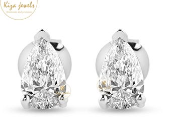 May include: A pair of diamond stud earrings. Each earring features a pear-shaped, clear diamond set in a silver or white gold setting. The earrings are displayed on a white background. The brand logo "Kiza Jewels" is in the upper left corner.