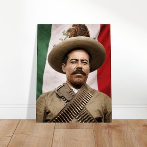 May include: A portrait of a man in a tan hat and military-style uniform, with a bandolier of bullets. The Mexican flag is in the background. The man has a dark mustache and is looking at the viewer.