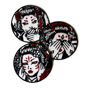 Peut inclure: Trois écussons ronds avec un motif de geisha en noir, blanc et rouge. Les geishas ont des accents rouges sur les lèvres, les yeux et les cheveux. Une geisha se couvre la bouche avec ses mains.