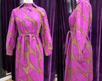 May include: A long-sleeved dress with a pink and brown abstract pattern. The dress has a button-up front, a collar, and a belt.