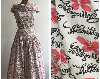 May include: A white dress with a pink and black butterfly print. The dress has a fitted bodice and a full skirt. The fabric is lightweight and has a vintage feel.