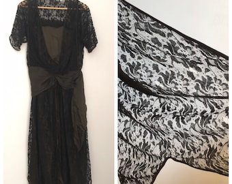 May include: A black lace dress with a brown satin lining and a matching brown satin sash. The dress has a V-neckline and short sleeves.