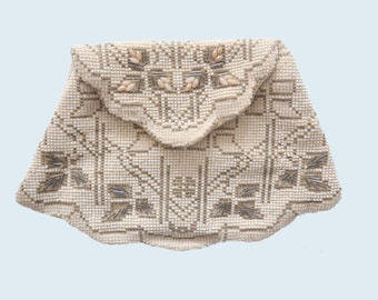 May include: A white beaded clutch purse with a scalloped edge and a geometric pattern. The purse is decorated with small, white shell-like beads and silver-colored beads.
