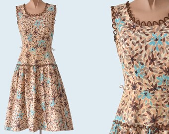 May include: A sleeveless dress with a brown and blue floral print. The dress has a round neckline and a tiered skirt. The neckline and the bottom of the skirt are trimmed with brown lace.