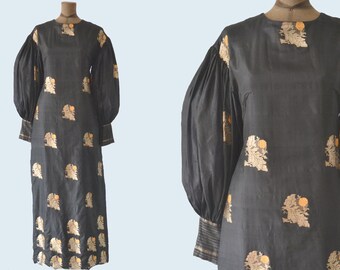 May include: A black long-sleeved dress with a round neckline and a gold floral pattern. The dress has puffed sleeves with gold trim at the cuffs.