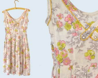 May include: A white sleeveless dress with a floral print in shades of pink, green, and gray. The dress has a yellow trim around the neckline and a gathered skirt.