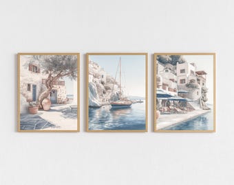 Peut inclure: Ensemble de trois impressions encadrées à l'aquarelle représentant des scènes côtières méditerranéennes. L'œuvre présente des bâtiments, un voilier et un arbre, dans des tons doux de bleu, beige et blanc. Les cadres sont marron clair, ajoutant à l'ambiance sereine.