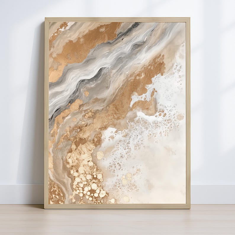 Op de afbeelding: Abstracte kunstafdruk in een kleurenpalet van goud, beige en grijs. Het kunstwerk toont vloeiende, gemarmerde patronen met accenten van bladgoud. De print is ingelijst in een licht houten frame, wat een moderne en elegante esthetiek cre&euml;ert.