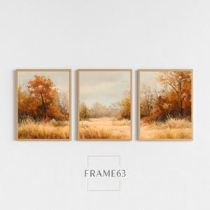 May include: Three framed landscape paintings depicting an autumn scene with golden fields and trees with orange and brown foliage. The artwork is set against a neutral background. The text "FRAME63" is at the bottom.