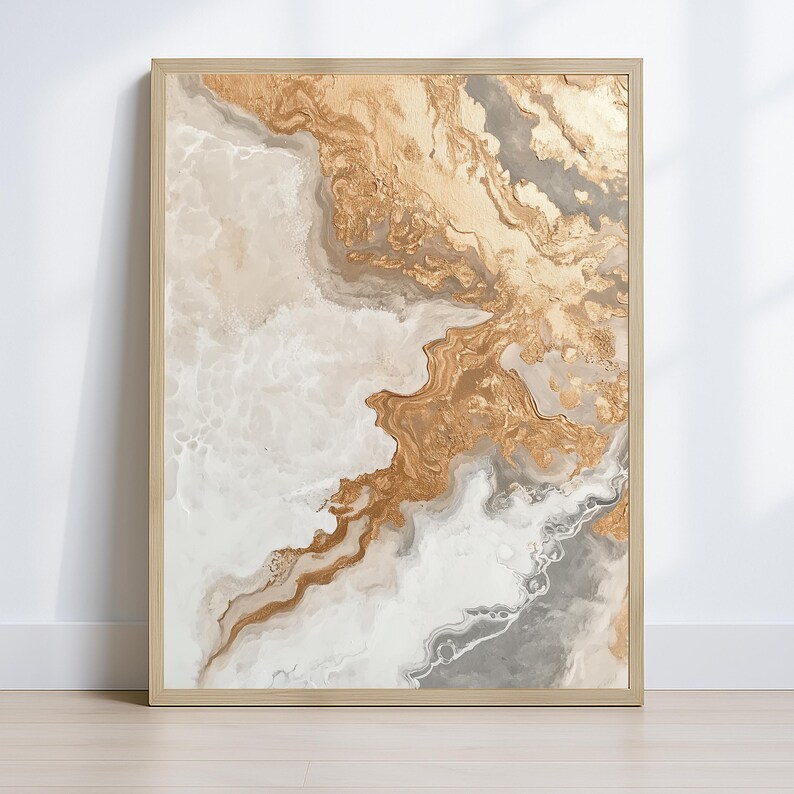 Op de afbeelding: Abstracte kunstprint in een kleurenpalet van goud, wit en grijs. Het kunstwerk heeft een vloeiend, gemarmerd ontwerp met gouden accenten, omlijst in een licht houten frame. Het stuk roept een gevoel van luxe en verfijning op.