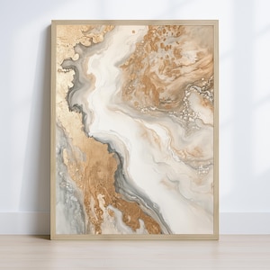 Op de afbeelding: Abstracte kunstafdruk in een kleurenpalet van goud, wit en grijs. Het kunstwerk heeft een vloeiend, gemarmerd ontwerp met metallic gouden accenten. De print is ingelijst in een licht houten frame, wat een vleugje elegantie toevoegt.