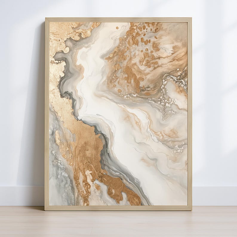 Op de afbeelding: Abstracte kunstafdruk in een kleurenpalet van goud, wit en grijs. Het kunstwerk heeft een vloeiend, gemarmerd ontwerp met metallic gouden accenten. De print is ingelijst in een licht houten frame, wat een vleugje elegantie toevoegt.