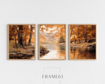May include: Three framed landscape art prints. Each print depicts a serene river scene with trees in autumn colors. The artwork features warm tones of gold, orange, and brown. The text "FRAME63" is at the bottom.