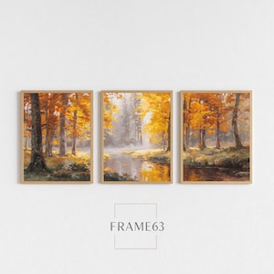 May include: Three framed landscape paintings depict an autumn forest scene. The artwork features trees with vibrant orange and yellow leaves, a river, and a misty atmosphere. The text "FRAME63" is at the bottom.