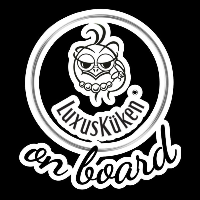 May include: A black and white sticker featuring a cartoon owl with a pearl necklace and a ring. The text "LuxusK&uuml;ken on board" is written in a stylized font, enclosed in a white circle.