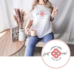 Peut inclure: T-shirt blanc avec l'inscription "women's rights first now all over the world" en noir et rouge. Le t-shirt présente un motif de trèfle à quatre feuilles. Le modèle porte un jean bleu et tient une tasse rose.