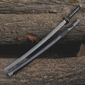 Op de afbeelding: Een katana zwaard met een zwart handvat en schede, rustend op een houten oppervlak met textuur. Het zilveren lemmet heeft een zichtbaar patroon. De schede is gedeeltelijk open en toont het lemmet. Het handvat is omwikkeld met zwart materiaal.