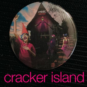 May include: A round button featuring the Gorillaz band's "Cracker Island" album art. The design includes cartoon figures in a surreal setting with a red-hatted character in the foreground. The text "cracker island" is displayed in pink.