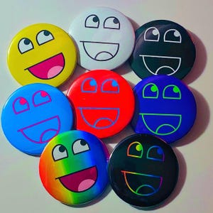 May include: A collection of nine colorful round buttons with a smiling face design. The buttons feature a variety of colors, including yellow, white, black, red, blue, green, and a rainbow gradient. Each button has a unique expression.