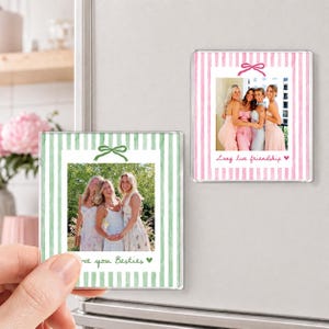Puede incluir: Dos imanes cuadrados para fotos con rayas verticales y un gr&aacute;fico de lazo. Un im&aacute;n tiene rayas verdes con el texto "love you Besties" y un coraz&oacute;n. El otro tiene rayas rosas con el texto "Long live friendship" y un coraz&oacute;n.