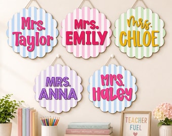 May include: Five circular scalloped wall signs with vertical stripes, each featuring a name and the title Mrs. The signs display the names Taylor, Emily, Chloe, Anna, and Haley in various colors and fonts, suspended by twine loops.