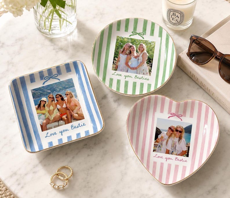 Puede incluir: Tres platos de cer&aacute;mica con bordes dorados, con rayas verticales en azul, verde y rosa. Cada plato muestra una fotograf&iacute;a personalizada de amigos y el texto escrito a mano "Love you Bestie" o "Love you Besties" con un peque&ntilde;o icono de lazo.