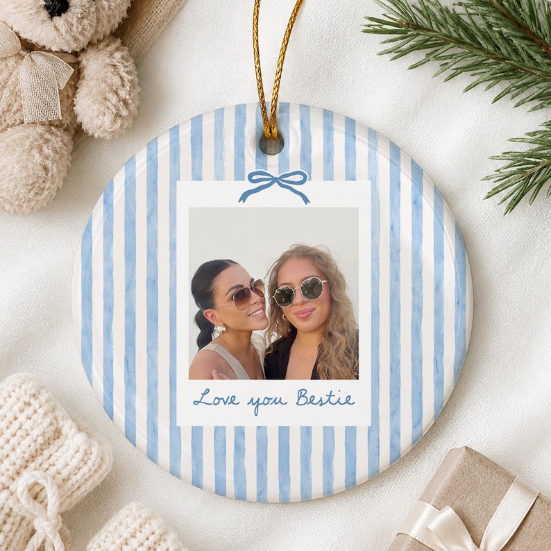 Puede incluir: Un adorno de cer&aacute;mica redondo con un patr&oacute;n de rayas verticales en azul claro y blanco. El centro muestra una foto cuadrada de dos personas con gafas de sol, enmarcada como una polaroid con un lazo azul y el texto Love you Bestie.